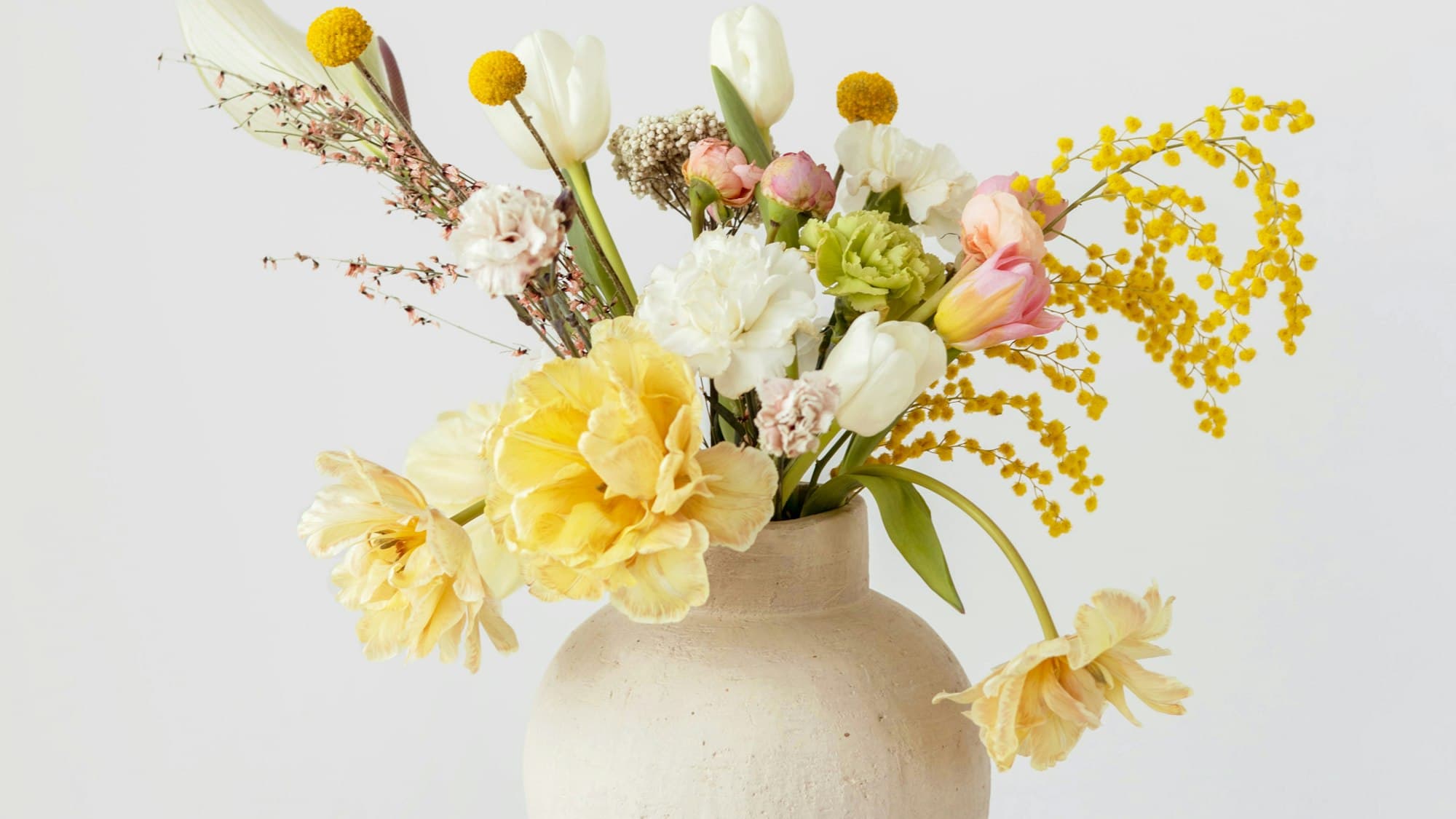 A styled arrangement of dried and permanent botanicals against a warm neutral backdrop